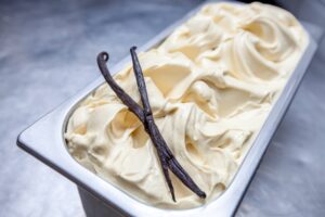 A tub of vanilla gelato with two vanilla pods.